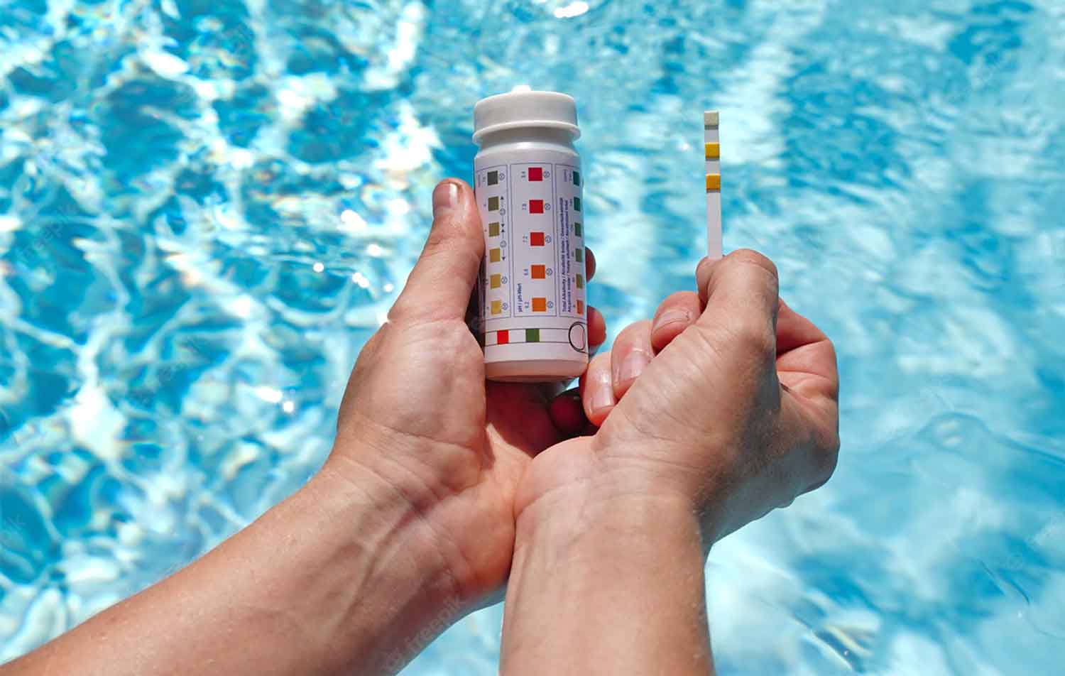 Persona comprobando el nivel de ph del agua de la piscina con tira reactiva.